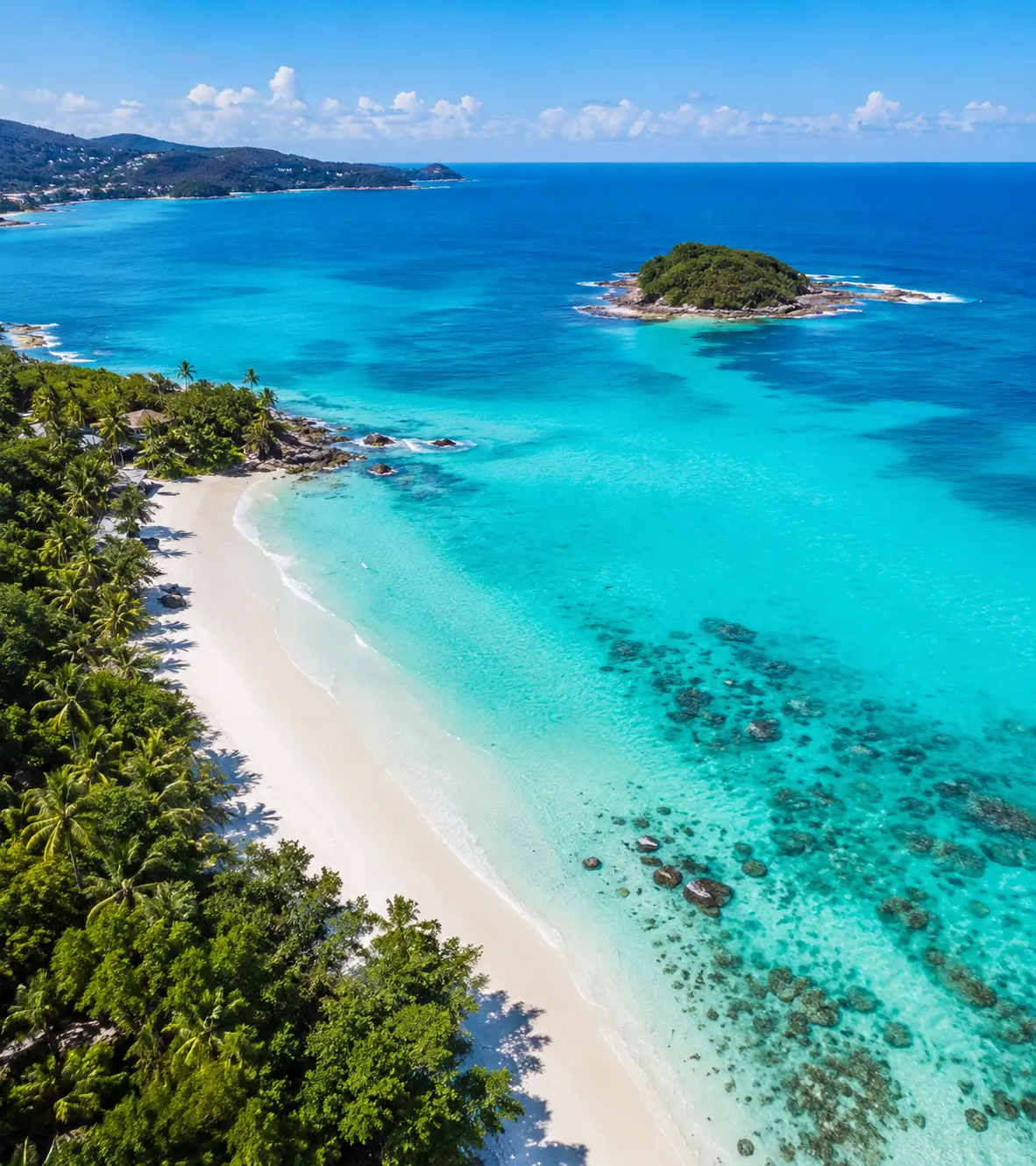 Aerial view of a tropical coastline with turquoise water and a white-sand beach